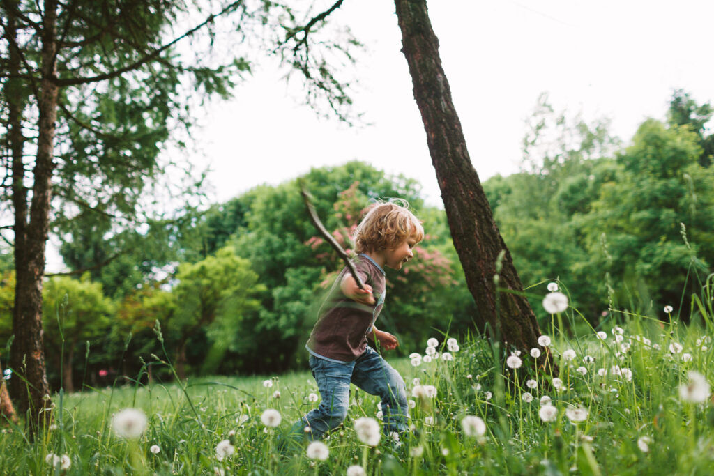 Jongen speelt in het bos tijdens een boswandeling met zijn ouders.