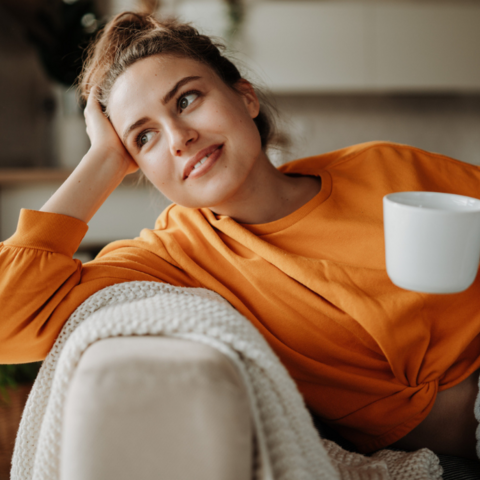 vrouw op bank kop thee deken