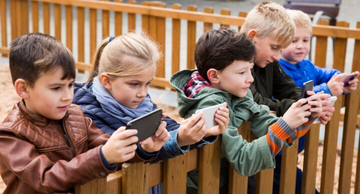 kinderen in speeltuin met smartphones telefoons Safer Internet Day social media