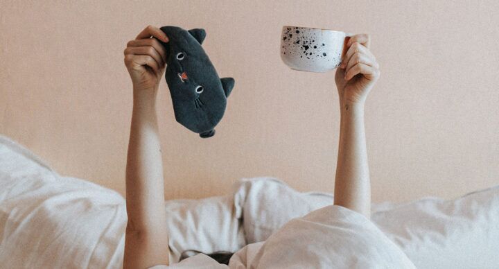 moeder in bed met slaapmasker en koffie slaaptekort