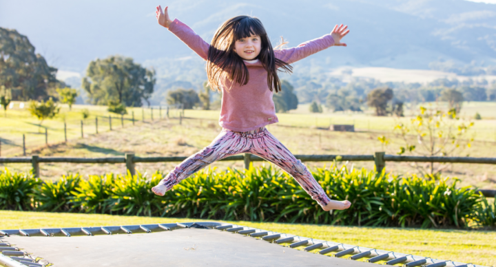 meisje in roze jurk springt op trampoline